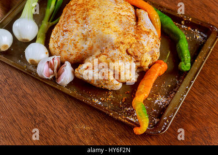 Tutto il pollo crudo condito con il burro e le erbe aromatiche per la tostatura. Vista dall'alto, dai toni vintage immagine marinato crudo intero pollo cucinare Foto Stock