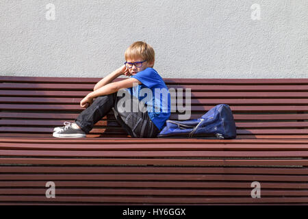 Scolaro con gli occhiali seduto sul banco dopo la scuola Foto Stock