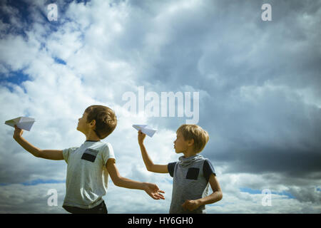 Ragazzi piccoli con piani di carta contro il cielo blu Foto Stock