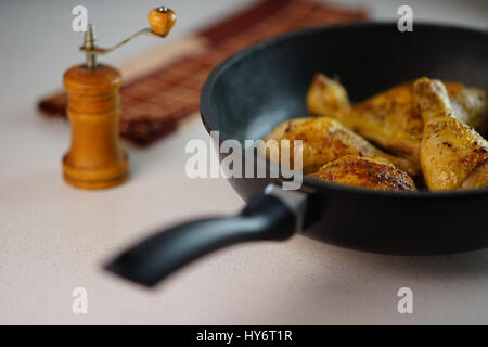 Fritto delizioso le cosce di pollo in una padella sul tavolo Foto Stock