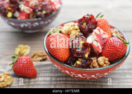 Turkish Delight con dadi e fragola in vaso in ceramica su sfondo di legno Foto Stock