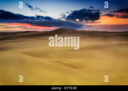 Dune di sabbia dorata di sunrise con gamme di colline di sabbia verso hoziron con red sky vicino Stockon spiaggia , NSW, Australia. Foto Stock