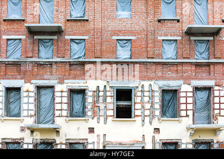 Parete di edificio di appartamenti in fase di ristrutturazione con coperte di windows Foto Stock