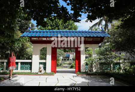 (170402) -- PALM BEACH, 2 aprile 2017 (Xinhua) -- una passeggiate turistiche passato il cancello del giardino cinese al Palm Beach è la società dei quattro arti in Palm Beach Island, gli Stati Uniti, il 24 marzo 2017. Essendo stato costruito nel 1938, i Giardini Botanici disegnati dalla sig.ra Lorenzo Woodhouse hanno servito come una guida per i nuovi proprietari di casa in cerca di ispirazione per paesaggistica le proprie case. A soli cinque minuti di distanza in auto, a Norton Museum of Art di West Palm Beach, una permanente esposizione cinese è anche imprimere ai suoi visitatori. (Xinhua/Wang Ying) (zy) Foto Stock