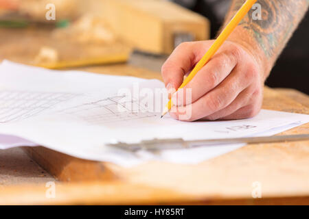 Close-up di falegname di piani e progetti scrive a disegni in officina Foto Stock