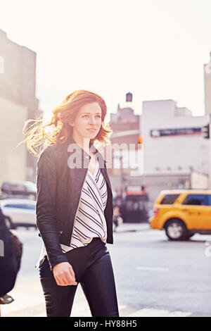 Le giovani donne a piedi lungo una New York street guardando lontano dalla telecamera in una giornata di sole Foto Stock