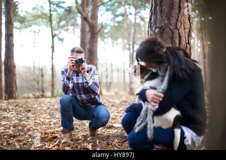 Un uomo prende una foto della sua compagna e il suo cane come si cammina nel bosco Foto Stock