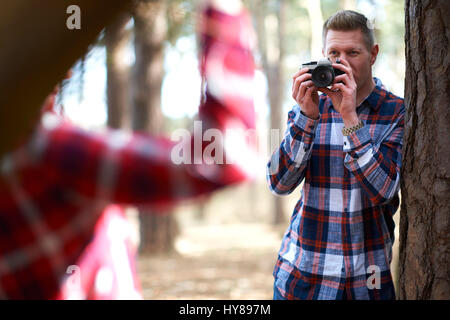 Un uomo prende una foto del suo compagno femminile come la passeggiata nel bosco Foto Stock