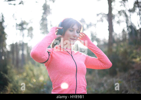 Una donna si prepara per andare a correre nei boschi Foto Stock