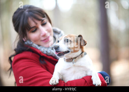 Una giovane donna trattiene il suo jack russell terrier Foto Stock