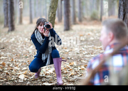 Una giovane donna assume una foto del suo partner nel bosco Foto Stock
