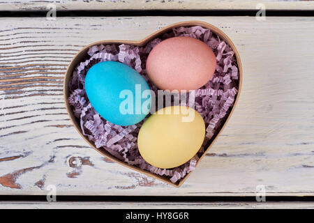 Regalo di pasqua sulla scatola di legno. Uova colorate in carta tagliuzzata. Arte ispirata dalla fede. Foto Stock