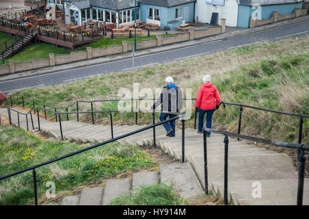 Un uomo maturo e la donna che cammina verso il basso i passaggi per l'area della spiaggia a Saltburn,l'Inghilterra,UK Foto Stock