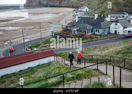 Un uomo maturo e la donna che cammina verso il basso i passaggi per l'area della spiaggia a Saltburn,l'Inghilterra,UK Foto Stock