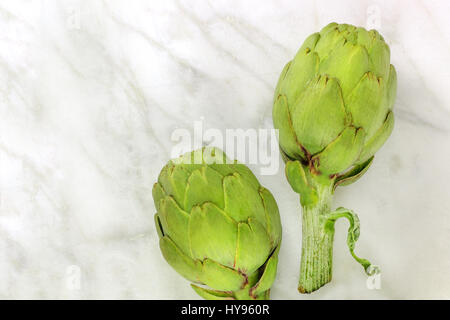 Carciofi su marmo bianco texture con copyspace Foto Stock