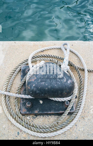 Primo piano di un ormeggio bollard e fune su un pontile sul mare Foto Stock