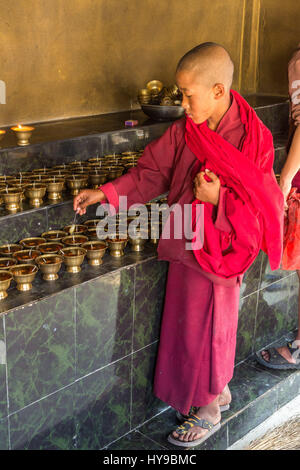 Un giovane monaco buddista prepara lampade a burro in Punakha Stupa in Punakha, Bhutan. Foto Stock