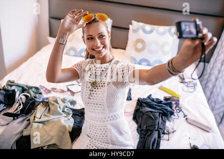 Femmina registrazione vlogger broadcast con fotocamera digitale. Donna prendendo un selfie visualizzando video moda abbigliamento e articoli di gioielleria. Foto Stock