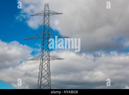 Guardando fino alla cima di alta torre di traliccio elettrico con cavi sospesi contro un cielo blu con bianche nuvole soffici, Scozia, Regno Unito Foto Stock