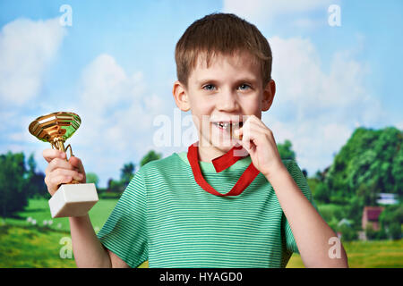 Ragazzo sportivo vincitore con la coppa e medaglia su sfondo natura Foto Stock