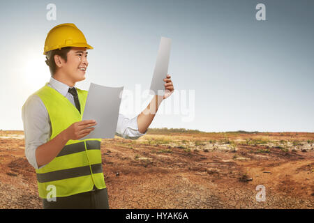 Ritratto di lavoratore asiatico l uomo cerca la sua blueprint al sito in costruzione Foto Stock