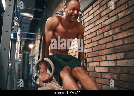 Focalizzato l'uomo utilizzando gli anelli di ginnastica Foto Stock