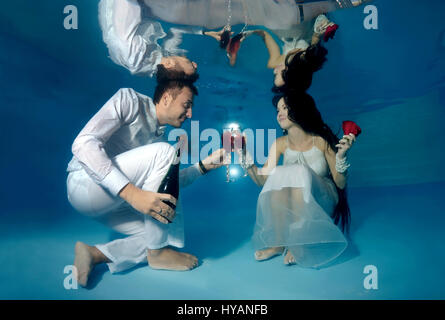 Tutti i round esclusivo. ODESSA, Ucraina: la sposa e lo sposo toast per il loro matrimonio. Gli sposi sono letteralmente prendendo il tuffo quando si tratta di commemorare il loro nuovo matrimonio. Jumping in all'estremità profonda, questi bizzarri immagini raccontano la storia del rapporto tra DJ Natalia Kol (26) e il Designer Viacheslav Kol (28) da Odessa, Ucraina, dal corteggiamento al matrimonio - mentre a tre piedi sott'acqua. Le immagini mostrano come lo sposo vince la sposa con una rosa rossa e va in giù su un ginocchio per la grande proposta. Possiamo anche vedere il make-up artist di andare a lavorare sul grande giorno, come ben come il primo ballo Foto Stock