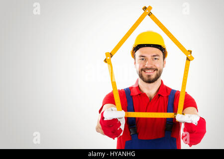 Home Improvement - tuttofare con casa righello sagomato in mani su sfondo grigio con spazio di copia Foto Stock