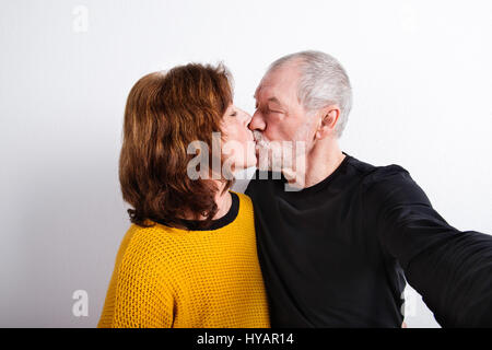 Coppia senior in amore kissing, tenendo selfie. Studio shot. Foto Stock