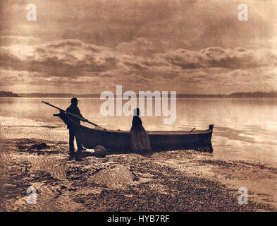 Questa fotografia della collezione di Edward S. Curtis cattura un individuo nativo americano in abiti tradizionali, mostrando la cultura e le tradizioni dei popoli indigeni del Nord America, come documentato nel lavoro di Curtis all'inizio del XX secolo. Foto Stock