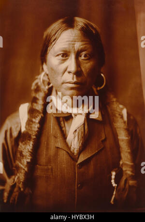 La fotografia di Edward S. Curtis 'A Jicarilla Man' del 1904, restaurata in seppia, cattura il ritratto di un uomo nativo americano della tribù Apache Jicarilla, mettendo in evidenza la sua identità culturale e l'abbigliamento tradizionale. Foto Stock