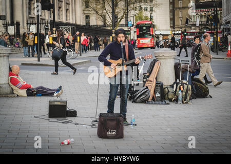 Musicista di strada/ performer/ cantante eseguendo con chitarra in Trafalgar Square, London, Regno Unito Foto Stock