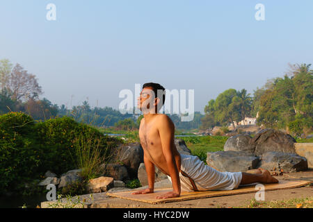 Uomo indiano a praticare yoga accanto a un fiume in India del Sud. Foto Stock