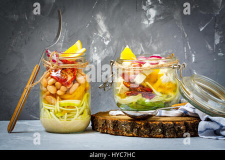 In casa jar pasta di zucchine con tofu, fagioli e verdure. Detox, dieta e vegetariano vegano pulire a mangiare cibo concetto. Sfondo grigio scuro, selezione Foto Stock