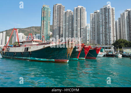 Commerciale barche da pesca ormeggiate nel canale di Aberdeen, alta edifici di appartamenti sull'Isola di Hong Kong dietro. Foto Stock