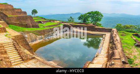 L'acqua nella cisterna sulla Roccia di Sigiriya riflette il cielo e alberi circostanti, Sri Lanka. Foto Stock