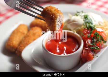 Uomo con gustose varietà Nugget e ciotola con la salsa sul tavolo, primo piano Foto Stock