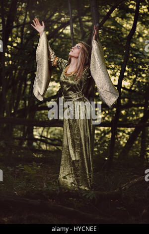 La donna in un bosco fiabesco con le braccia al cielo. Dark fantasy Foto Stock