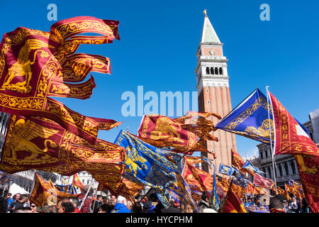Celebra la festa del santo di Venezia in Piazza San Marco con le bandiere e gli striscioni su una ventilata giornata di sole Foto Stock