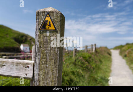 Fishguard, Galles - Pericoloso cliff triangolo di segnalazione segno sulla via costiera Foto Stock