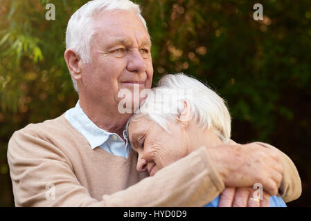 Romantico uomo senior abbraccia calorosamente la sua donna al di fuori Foto Stock