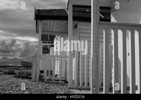 Cabine sulla spiaggia, sulla ghiaia a Pevensey. Monocromatico. Foto Stock