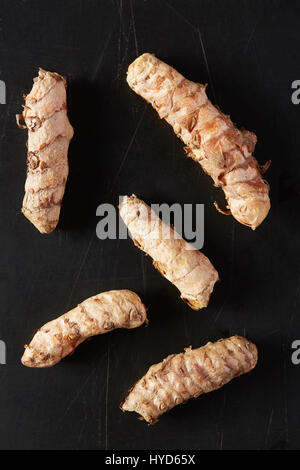 Radici turmeriche su sfondo nero Foto Stock