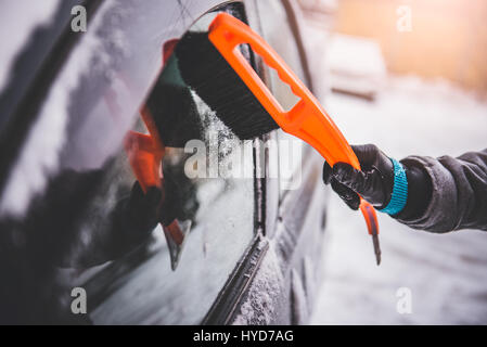 Donna di pulizia di una coperta di neve auto con ghiaccio in plastica raschiatore di neve Foto Stock