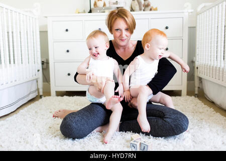 Ritratto di madre che tiene figli (12-17 mesi) in asilo nido Foto Stock