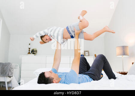 Padre e figlio (4-5) giocano in camera da letto Foto Stock