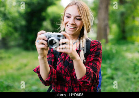 Giovane donna che scatta foto nel parco Foto Stock