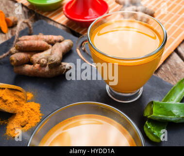 Bevanda calda con aloe vera e la curcuma. Le coppe di vetro su un vassoio di ardesia Foto Stock