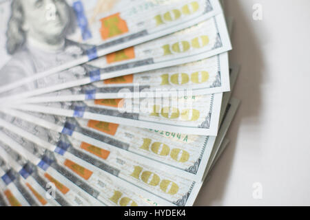 Un primo piano consente di visualizzare di nuovo di zecca banconote da cento dollari in valuta statunitense ventaglio su un tavolo bianco Foto Stock