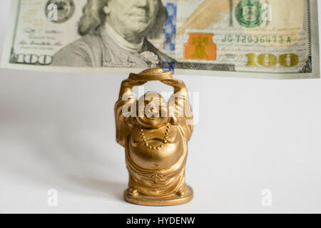 In prossimità di un piccolo golden BUDDA STATUETTA tenendo un centinaio di dollari in valuta degli Stati Uniti sopra la sua testa Foto Stock